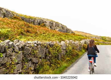 Girl Biking Down Road In Inis Mor