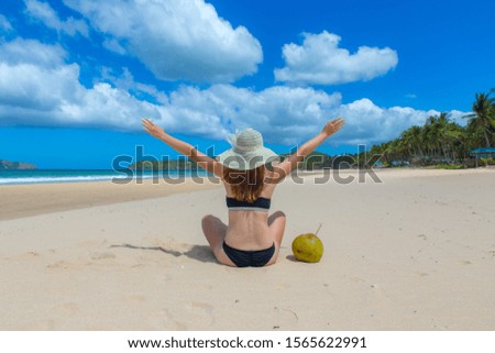 girl in bikini drinks coconut juice on a paradise beach