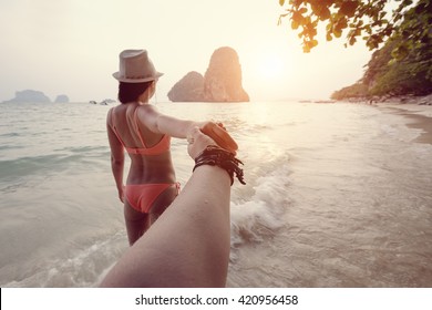Girl in a bikini holding a hand Man on the beach in Thailand