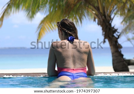 girl in bikini in a tropical pool looking at the ocean