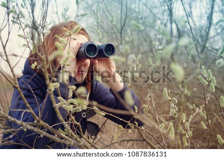 Girl with the binoculars against the background of the nature. Observation of birds. Birdwatching