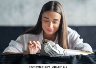 Girl With Bionic Arm Using Phone, Reading Social Media And Chatting In Bed, Woman With Disability Learning Or Working Online Remotely From Home