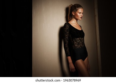 Girl In Black Bodysuit With Tight Hair In The Ponytail, Posing In The Studio, Looking At The Side.