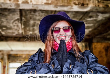 Girl in a black cloak and hat posing in an abandoned, ruined house. Unusual photoshoot