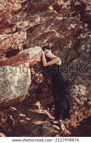 Similar – beautiful brunette short hair girl leaning against  gray rock wall outdoors, wearing black clothes