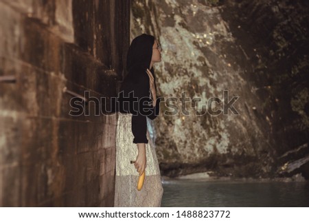 beautiful brunette short hair girl leaning on gray rock wall outdoors smiling happy