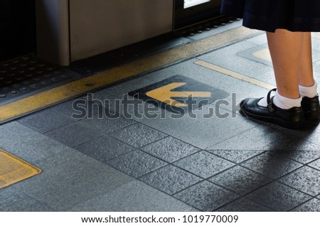 Girl in black leather shoes stands in front of the door with point arrow