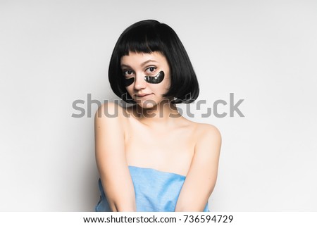 girl with black mask on her face posing against white background