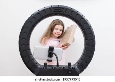 a girl blogger, in the center of a circular lamp and a smartphone, makes a review of the package for unpacking - Shutterstock ID 1957993048
