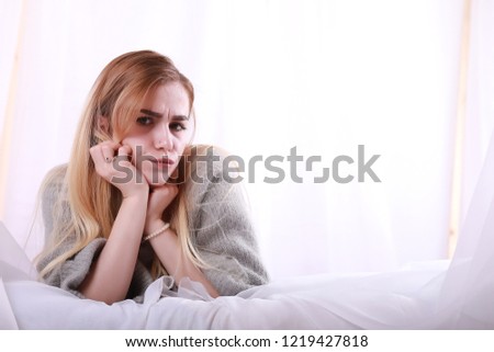 Girl with blond hair and gray sweater poses
