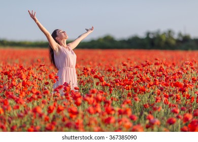 Girl at blooming poppy field. Young woman posing in poppy field in evening time