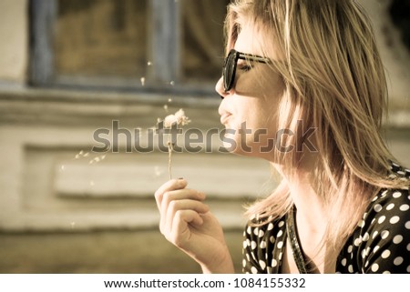 Girl blowing on a dandelion. Blowing of dandelion seeds.