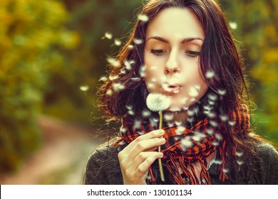 Girl Blowing On White Dandelion In The Forest