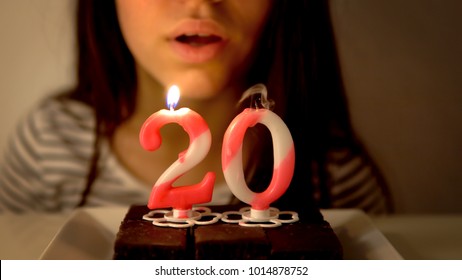 Girl Blowing Out A 20th Birthday Candle On A Cupcake