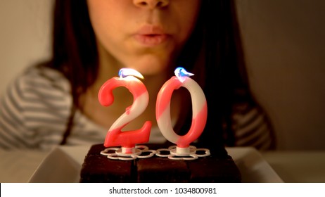 Girl Blowing Out A 20th Birthday Candle On A Cupcake