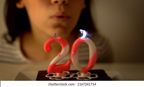 Girl Blowing Out A 20th Birthday Candle On A Cupcake