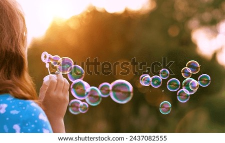 girl blowing soap bubbles outdoor, abstract natural background. rear view. dreaming, harmony peaceful atmosphere. Happy childhood concept. template for design. selective focus