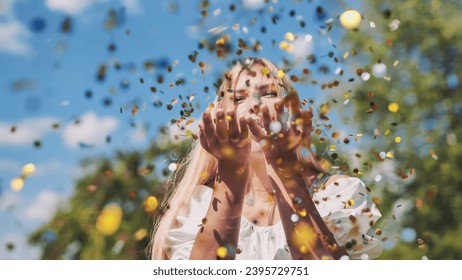 The girl blows a golden confetti out of her hands. - Powered by Shutterstock