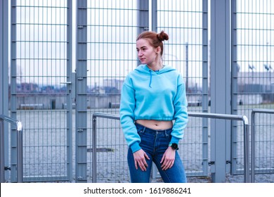 Girl in a blue crop top. Stylish streetwear for teens. Shooting near the gray grid. Blue jeans.