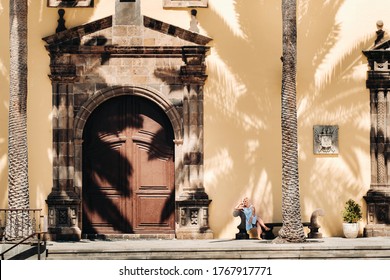 A girl in a blue dress sits on a bench in the old town of Garachico on the island of Tenerife on a Sunny day.A tourist walks in the old town on the island of Tenerife Canary Islands.Spain