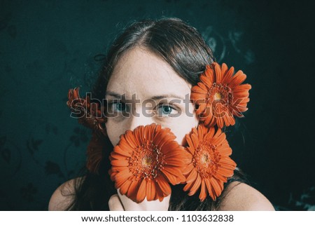 a girl with blue eyes and long hair with a beard of gerbera flowers