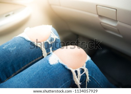 Girl in blue jeans sitting in the car