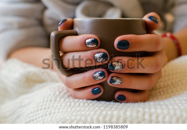 青い爪のマニキュアを持つ女の子はコーヒーを入れ 女性はレトロなセーターを着る マニキュアと美のコンセプト 茶色の爪マニキュアを持つ 接写 限定フォーカスガールがコーヒーを机の上に置く の写真素材 今すぐ編集