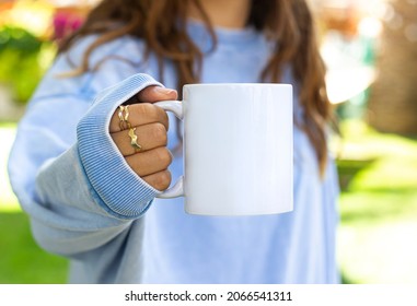 Girl in blue sweatshirt holding white coffee mug , white porcelain mug mock up for your design
