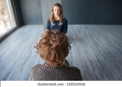 Girl With Blurred Face Sitting Opposite Another Person. No Faces In A Focus. Couch Session Of A Young Woman