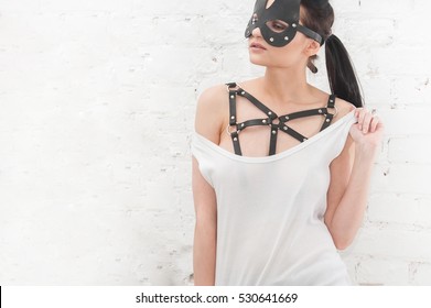 A girl in a body harness and a mask 