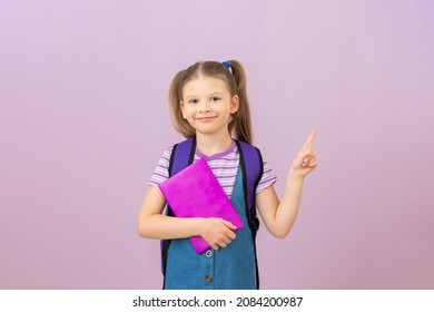 A girl with a book in her hands points her finger at your advertisement. a schoolgirl with a book on an isolated background. - Powered by Shutterstock