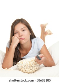 Girl Bored Watching Boring Movie In Bed. Funny Image Of Woman Lying Down In Bed On White Background Eating Popcorn And Zapping Changing Channel On Tv.