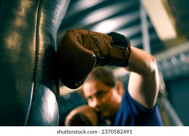 a girl boxer in gloves works out the strength of punches on a punching bag in the gym trains hard before fight close-up