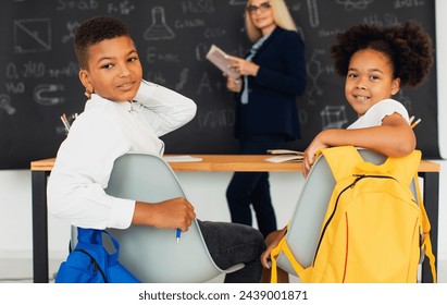 A girl and a boy, African-American school children, solve problems with the teacher during a lesson. Back to school. - Powered by Shutterstock