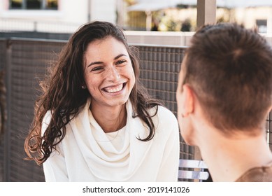 a girl and a boy are flirting, she looks at him and smiles fascinated by him, focusing on the girl - Flirting and Love Concept