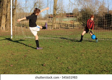 Girl And Boy Playing English Football On Countryside Sports Field, UK