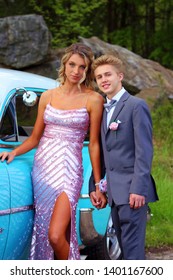 Girl And Boy Posing For High School Senior Prom Photos With Old Blue Car With White Hood No Logos