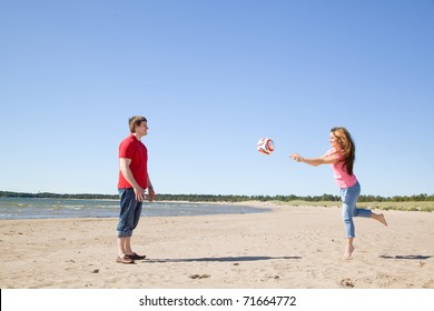 Girl And Boy Throwing A Ball On A Beach