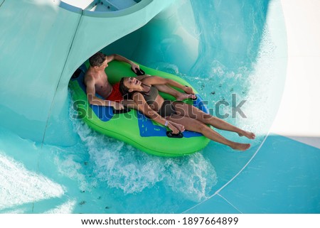 Girl and boy in water Park. Fun on the water. Teen girl and boy having fun in the water slider . Happy children's vacation outdoor.