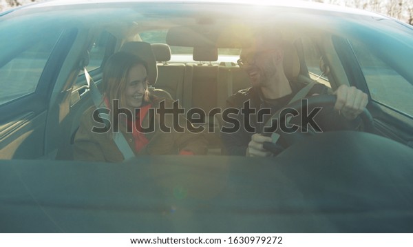 Girl and boyfriend
sitting in car and talking to each other. Young people enjoying
spending time together. Out of town. Happy relationship, traffic,
drive, business