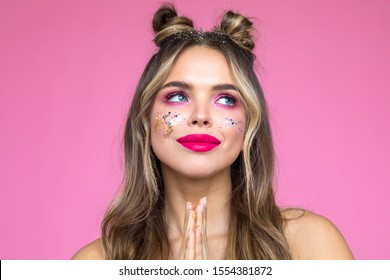 Girl with bright makeup on a pink background. Glitter Makeup.