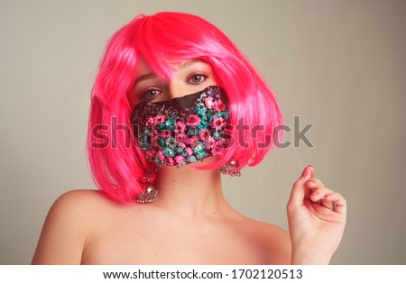 Girl with bright pink hair, anime, in a mask of flowers. Spring, joy, people should wear masks. Fashionable girl in a mask. Portrait of a bright girl in the studio. Spring, coronavirus, pandemic.