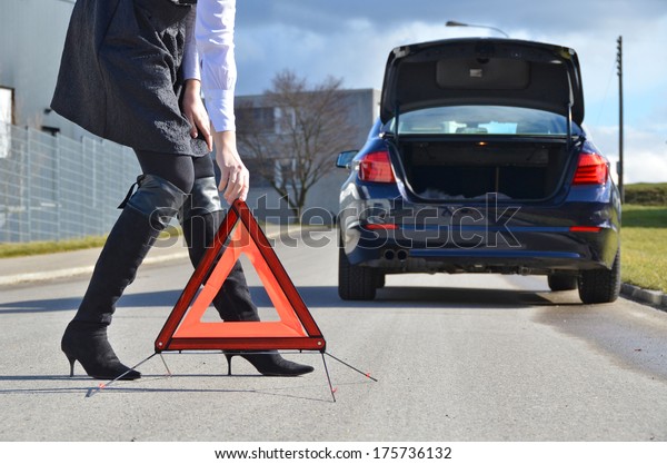 Girl, broken car and\
warning triangle