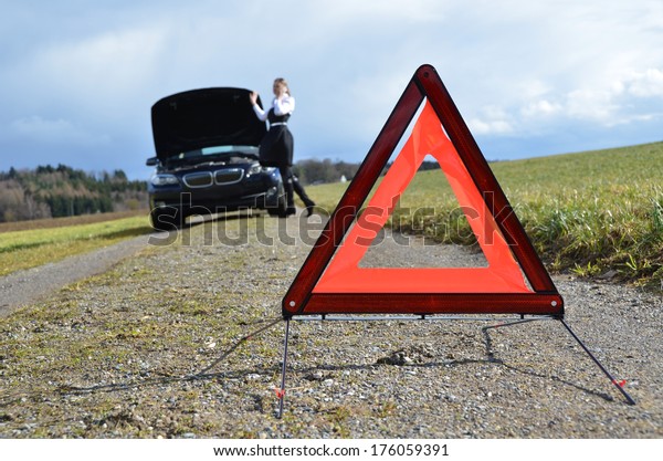 Girl, broken car and\
warning triangle 