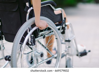 A Girl With A Broken Leg Sits In A Wheelchair.