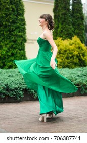 girl brunetka . Dressed in a beautiful green dress , ball . beautiful hair and make-up Golden purse - Shutterstock ID 706387741