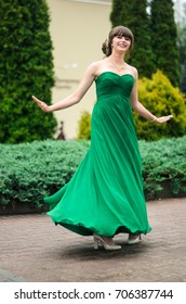 girl brunetka . Dressed in a beautiful green dress , ball . beautiful hair and make-up Golden purse - Shutterstock ID 706387744