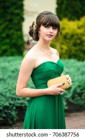 girl brunetka . Dressed in a beautiful green dress , ball . beautiful hair and make-up Golden purse - Shutterstock ID 706387756