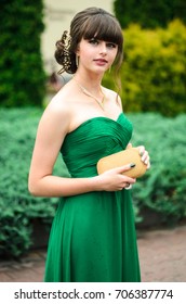 girl brunetka . Dressed in a beautiful green dress , ball . beautiful hair and make-up Golden purse - Shutterstock ID 706387774