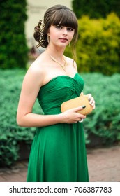 girl brunetka . Dressed in a beautiful green dress , ball . beautiful hair and make-up Golden purse - Shutterstock ID 706387783